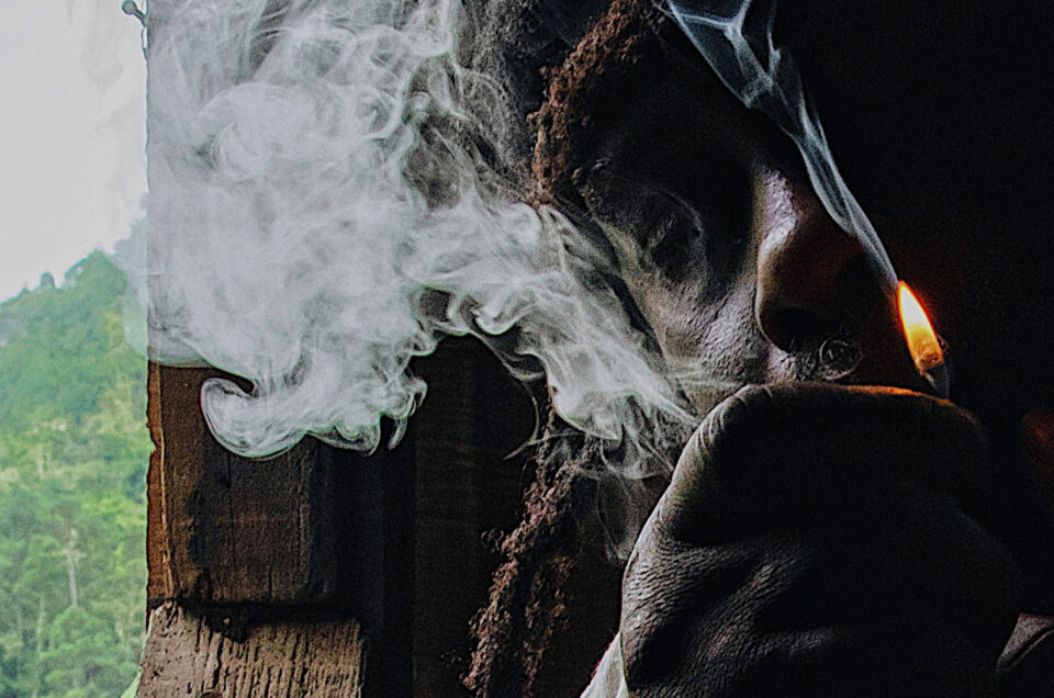 Rastafarian in thoughtful repose by an open window overlooking the lush Blue Mountains of Jamaica.