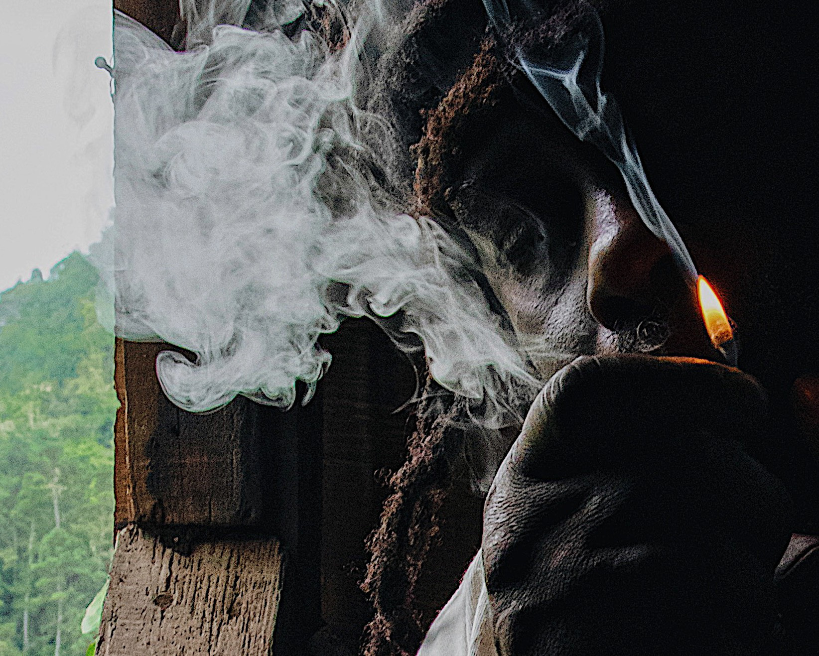 Rastafarian in thoughtful repose by an open window overlooking the lush Blue Mountains of Jamaica.